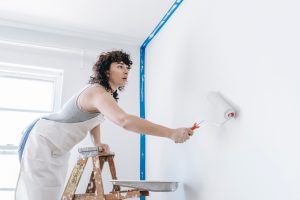 woman standing on ladder to paint a wall