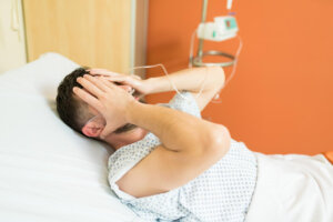 A man lying in a hospital bed looking upset