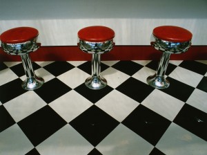 Red stools on a black and white vinyl tile floor (Getty Images/Visions of America)