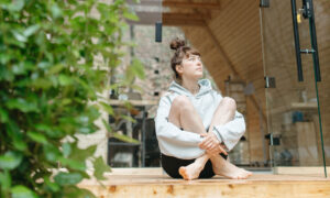 A woman alone on the porch of her cottage, looking up as she's deep in thought.