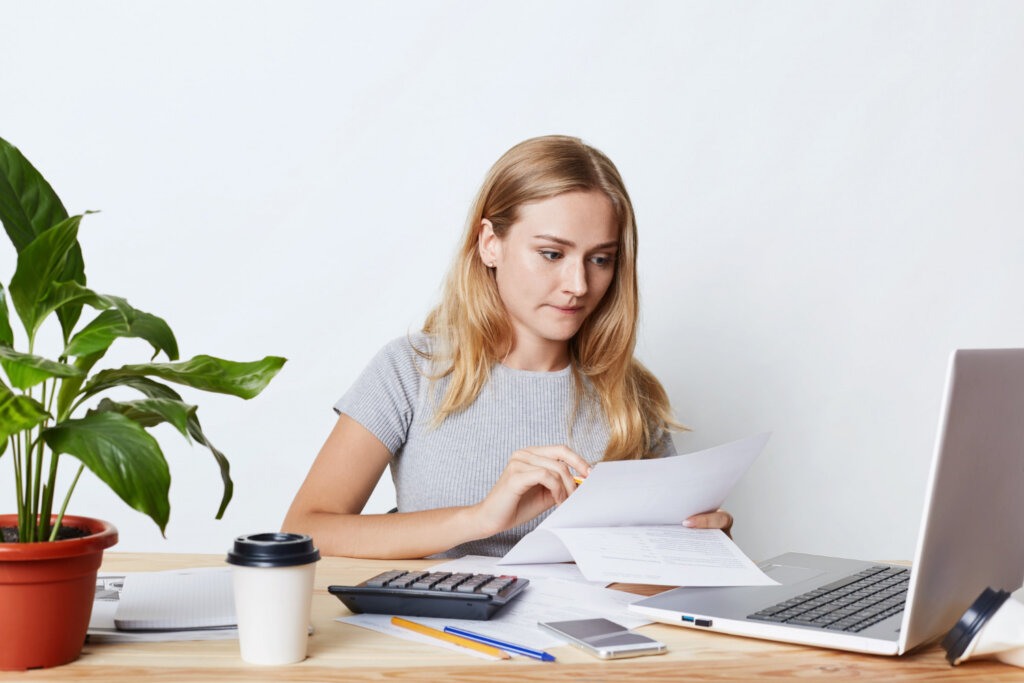 A young woman studies an insurance policy at her desk