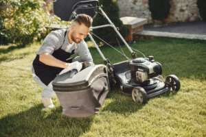 A young man empties a lawn mower bag