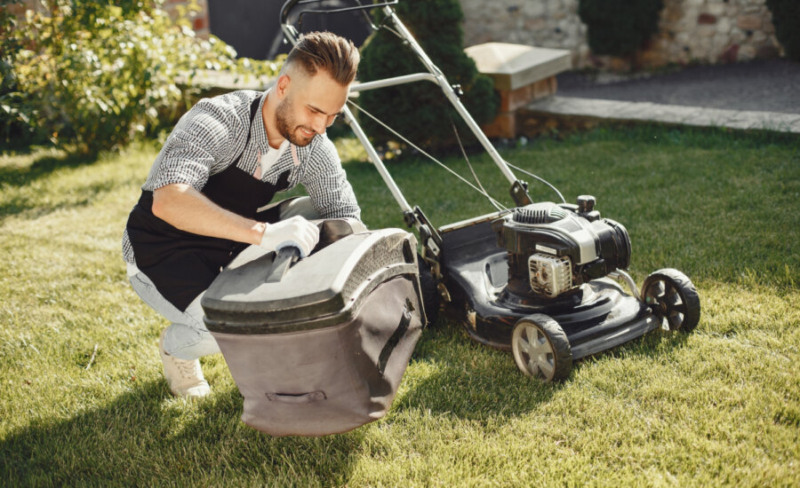 A young man empties a lawn mower bag