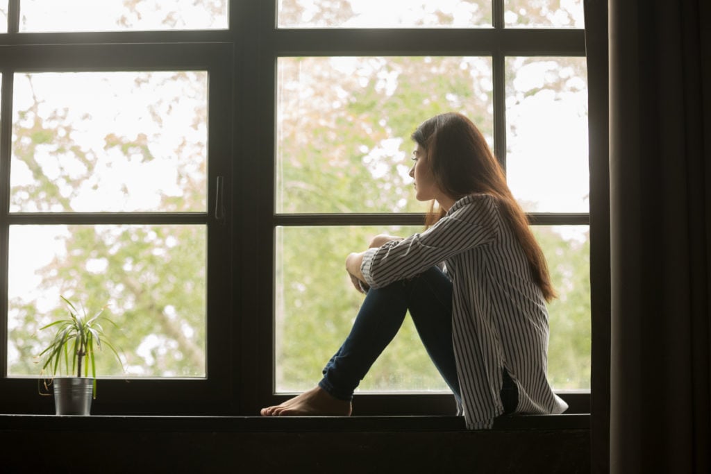 A woman is seen sitting in of a window