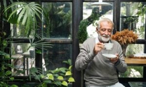 A old man is seen drinking from a cup