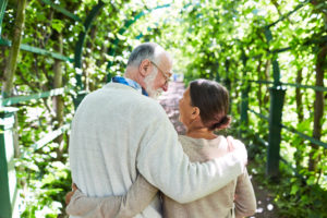 A older couple walking in a forest enjoying sunny day