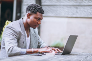 A man is seen staring at a laptop intensely with a concerned look on his face