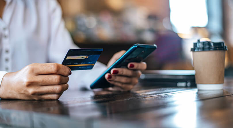 a woman holding a debit card and a phone