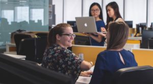 a woman sitting at a desk chatting with friends