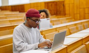 A student works on his laptop in an empty lecture hall