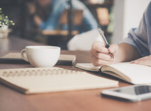 Woman having a coffee and writing notes