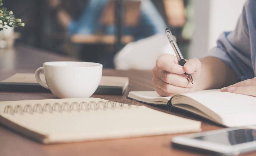 Woman having a coffee and writing notes