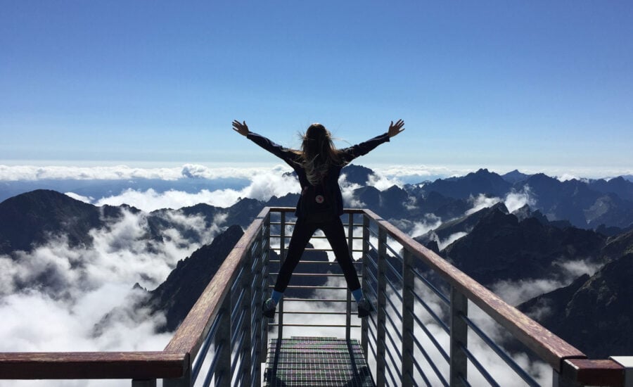 woman at the top of a mountain cheering, as an allegory to defeating debt