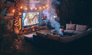 The ultimate backyard fire pit, surrounded by an outdoor sectional sofa and a big movie screen