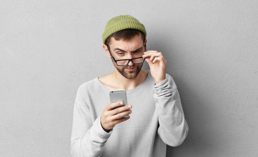 A man lowering his glasses to read a message on his phone