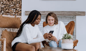 two roommates going over the photos of their belongings on a cell phone