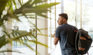 A student walking out of a building, thinking about his financial situation