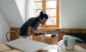 A man at home, scrolling his computer for the best TFSA rates
