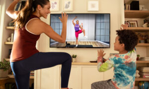 A woman doing a workout with her son, using the Peloton app. They're laughing because working out is fun, no?