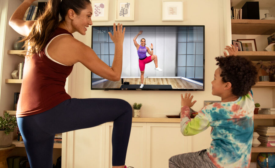 A woman doing a workout with her son, using the Peloton app. They're laughing because working out is fun, no?