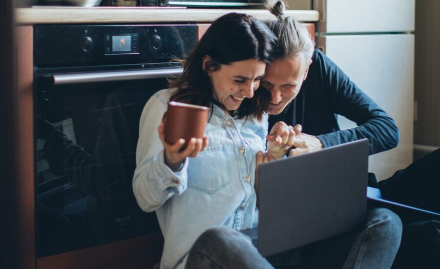 Couple sitting on kitchen floor looking at laptop