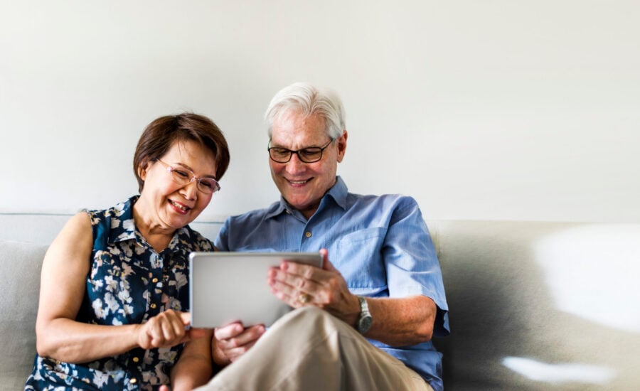 Senior couple using a digital device in a living room