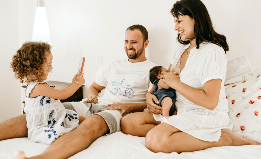 A young family sitting together on a bed laughing, 'cause life's good!