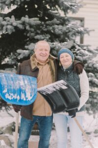 senior couple shovelling snow outside their home