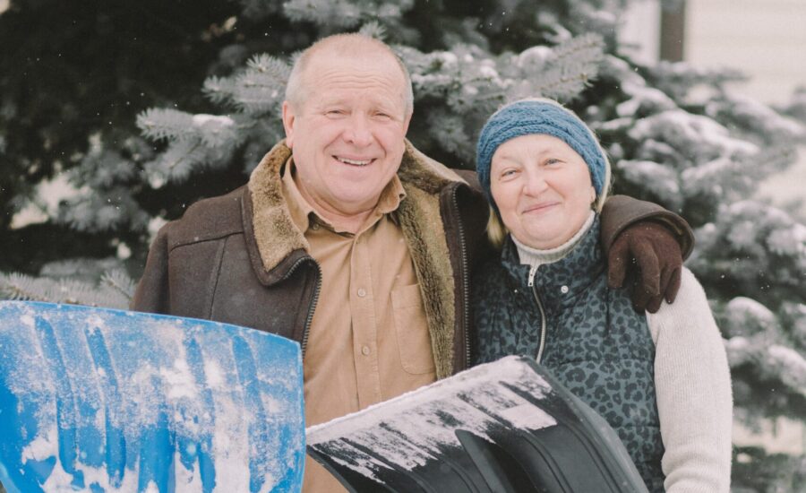 senior couple shovelling snow outside their home