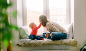 A toddler holds their mom's face in their hands. So cute!