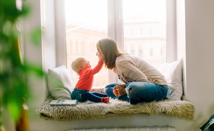 A toddler holds their mom's face in their hands. So cute!