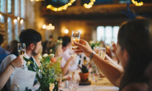 A long table of wedding guests with a glass of champagne raised to toast the couple