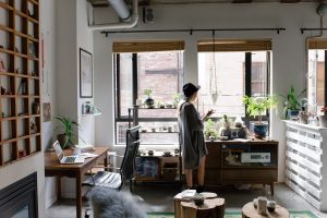 woman standing by window in her home office