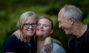 An older couple with their young adult son, who has down syndrome.