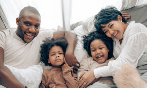 A family with young children laughing on a couch