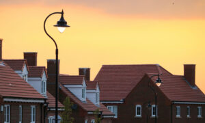 The sun is setting on a row of houses on a suburban street.