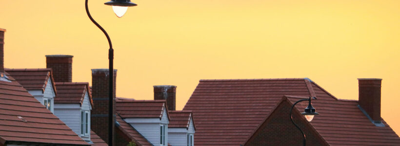 The sun is setting on a row of houses on a suburban street.