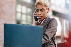 concerned woman speaking on cellphone and looking at laptop