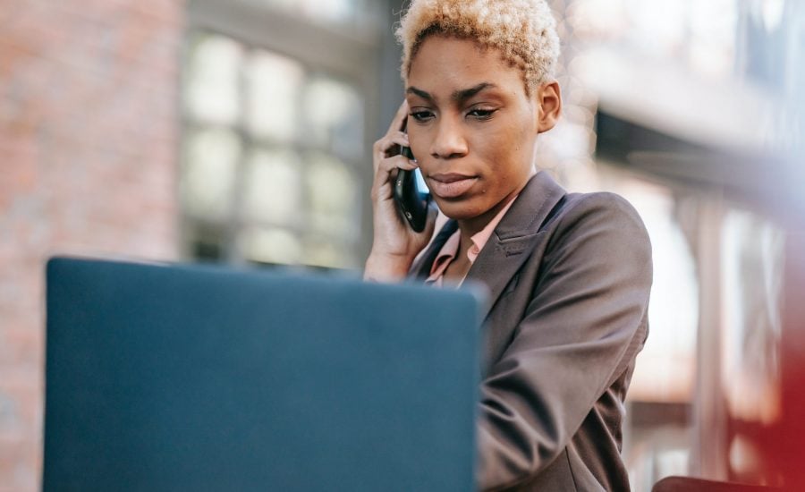 concerned woman speaking on cellphone and looking at laptop