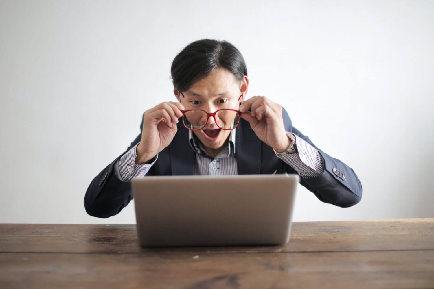 Man with glasses looking surprised at computer monitor