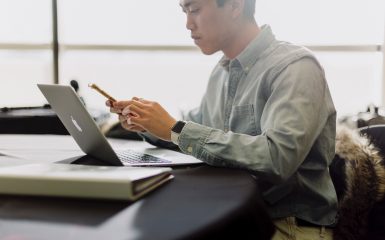 man looking concerned while reading on mobile phone and laptop