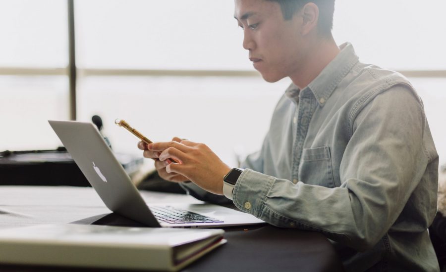 man looking concerned while reading on mobile phone and laptop