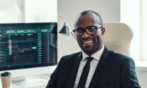 A man sits at his desk smiling