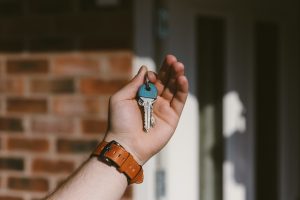 close-up of hand holding keys with home in background