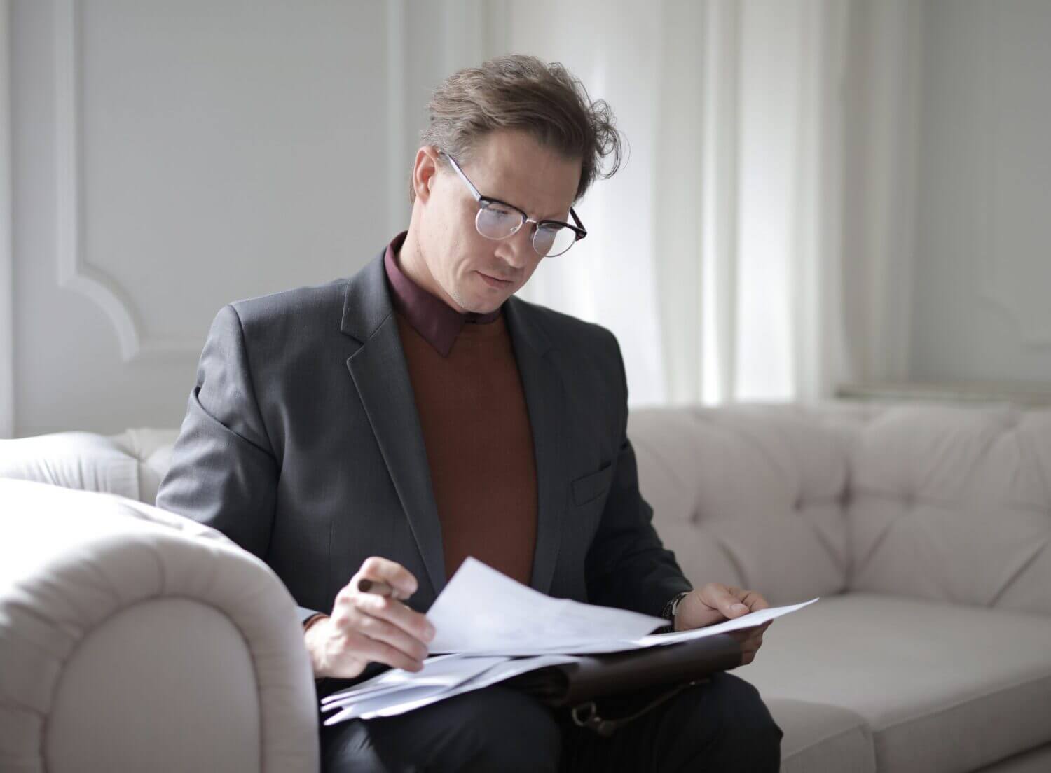 man sitting on couch reading paperwork