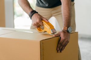 man taping a moving box closed