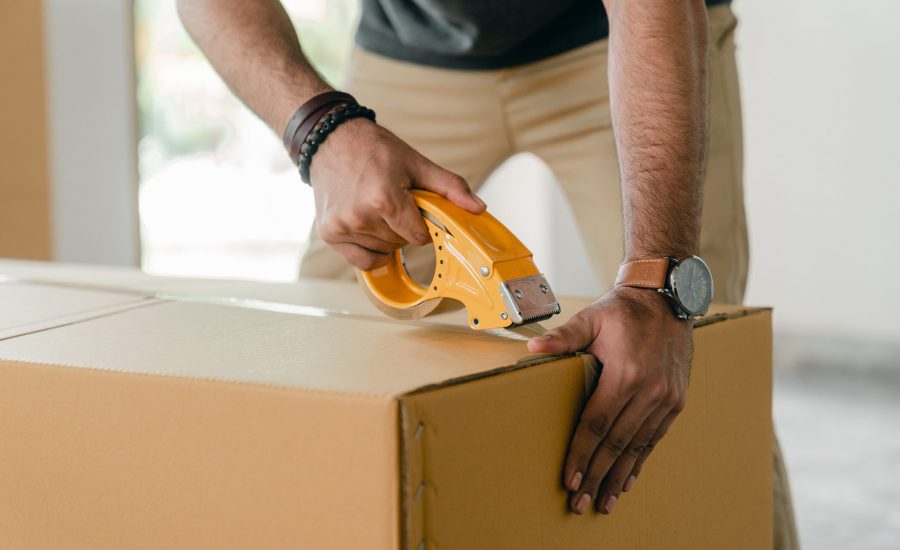 man taping a moving box closed