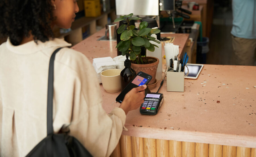 A woman is buying a coffee at an artisanal café, using her KOHO credit card.