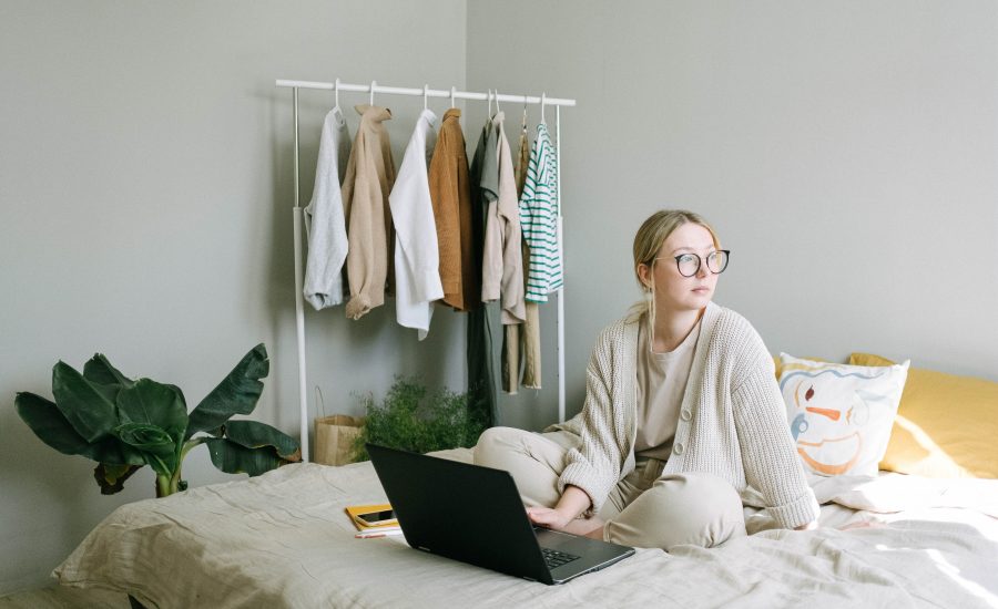A young woman sits on her bed, compares home insurance quotes on her computer