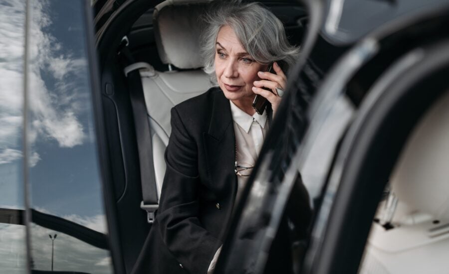 grey-haired woman listening to mobile phone in car